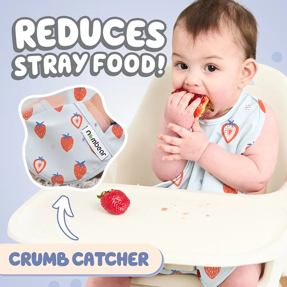 Baby Eating a Strawberry Wearing a Blue Bib. Reduces Stray Food! With Crumb Catcher.