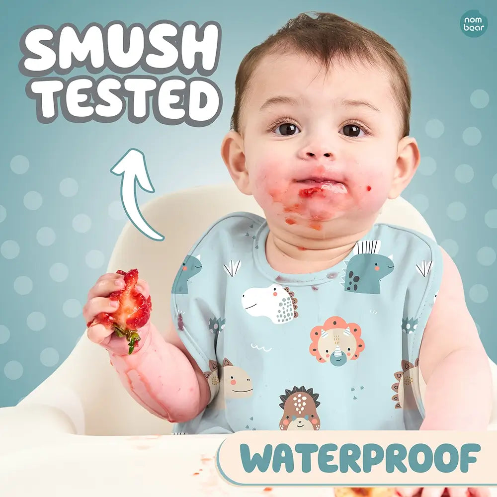 Baby Wearing a Bib with Dinosaurs Pattern, Smushing a Strawberry. Smush Tested. Waterproof.