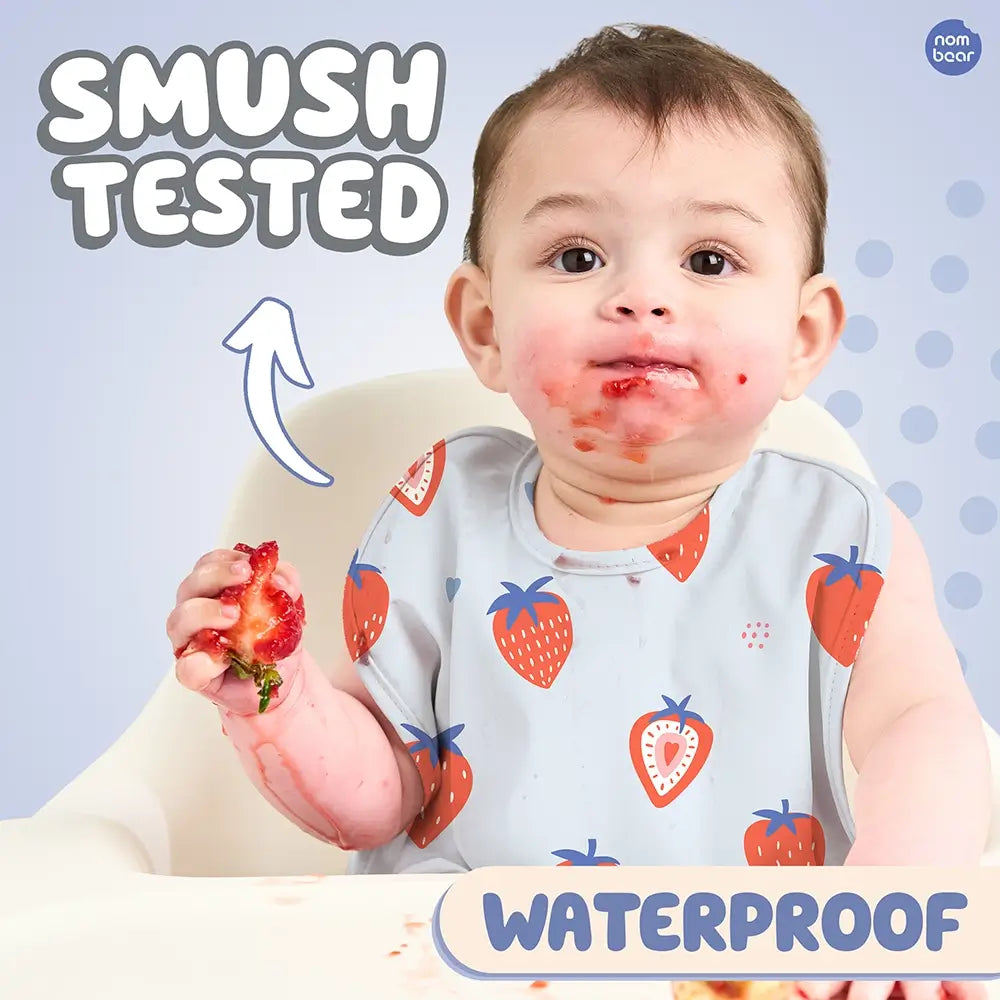 Baby Wearing a Bib with Blue Strawberries Pattern, Smushing a Strawberry. Smush Tested. Waterproof.