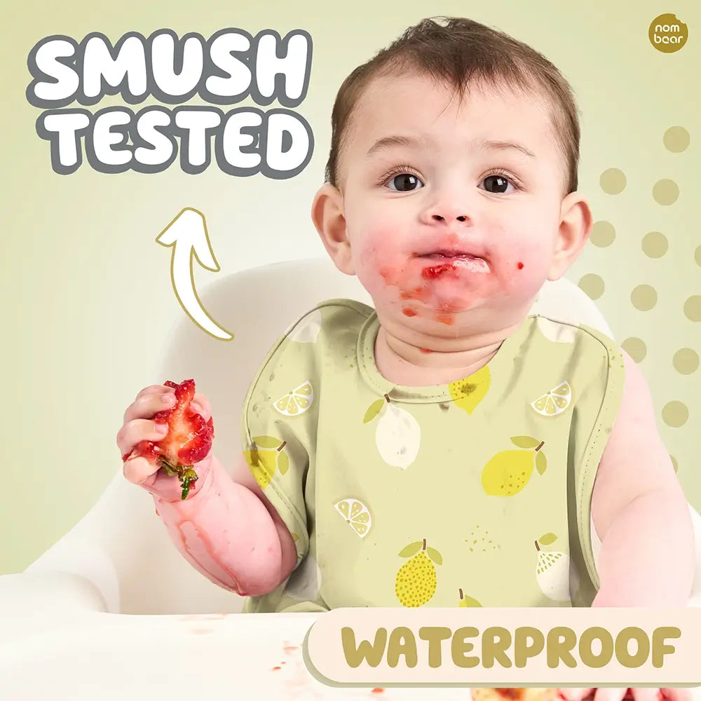 Baby Wearing a Bib with Lemons Pattern, Smushing a Strawberry. Smush Tested. Waterproof.